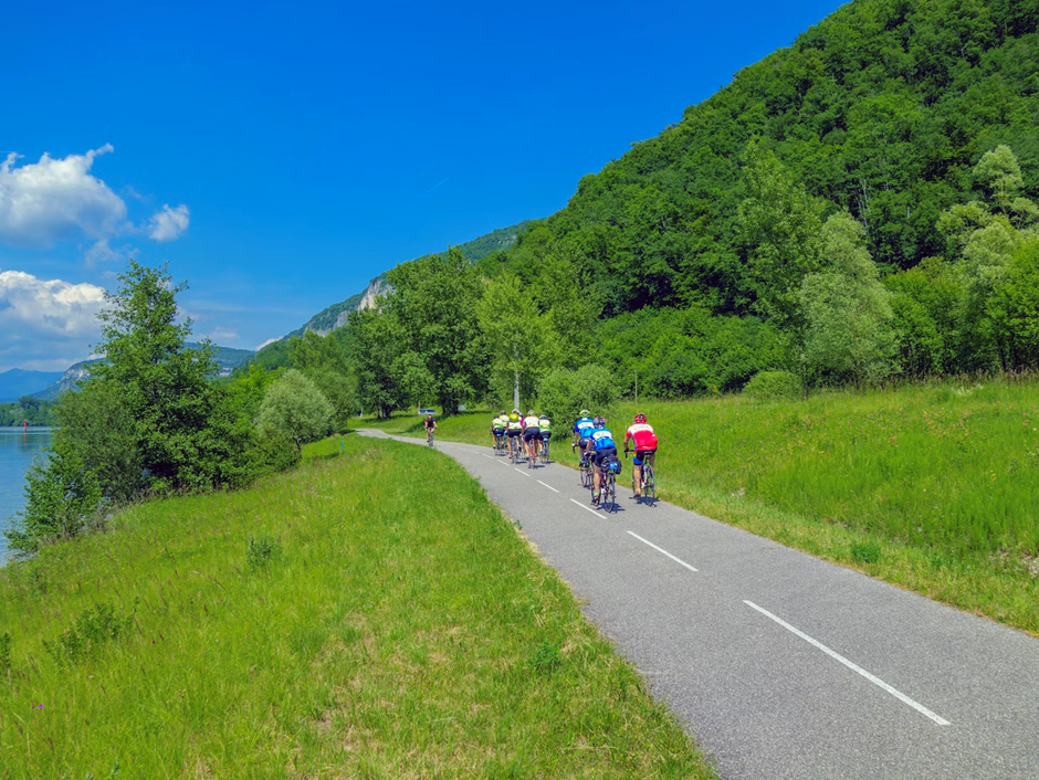 Skupina ľudí jazdiacich na bicykloch po ceste vedľa jazera